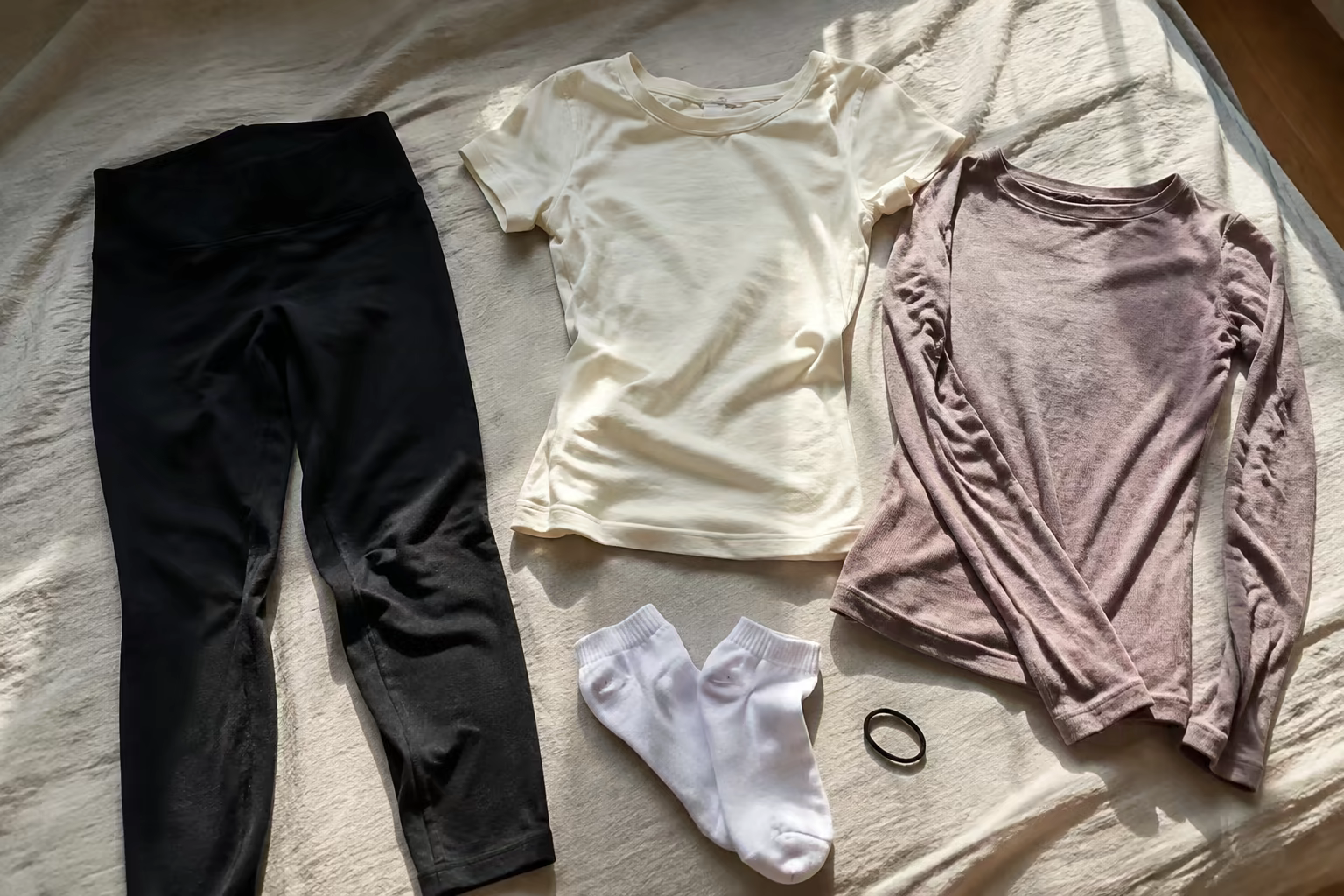 Legging sombre, tee-shirt ajusté, haut fin, chaussettes et élastique disposés simplement à la lumière du jour